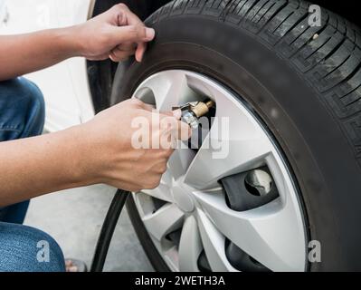 homme remplissant la pression d'air dans le pneu de voiture gros plan Banque D'Images