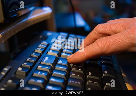 Gros plan de l'homme doigt appuyant sur la touche entrée sur un clavier d'ordinateur sur fond de maison doux Banque D'Images