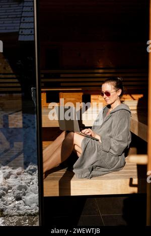 Femme assise avec ordinateur portable dans le sauna Banque D'Images