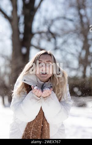 Portrait jeune femme joyeuse dans des vêtements d'hiver chauds s'amusant dans la forêt d'hiver parmi les arbres Banque D'Images