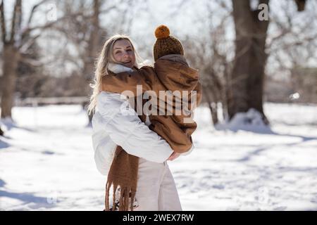 Activités familiales en plein air pour de joyeuses vacances d'hiver. Mère heureuse et deux fils jouant des boules de neige sur la rue enneigée en banlieue. Famille heureuse sur Winter Wee Banque D'Images