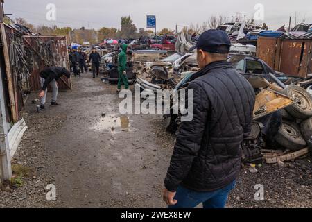 Homme à la recherche de pièces de voiture à la junkyard à ciel ouvert et utilisé le marché des pièces de rechange à Kudaybergen, Bichkek, Kirghizistan Banque D'Images