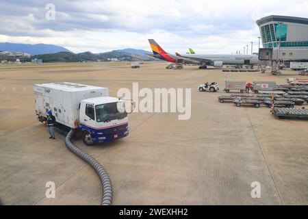 Une unité d'alimentation au sol est attachée à un avion de ligne moderne stationné dans un parking d'aéroport. Avant de voler, l'aéronef subit des opérations de maintenance et Banque D'Images