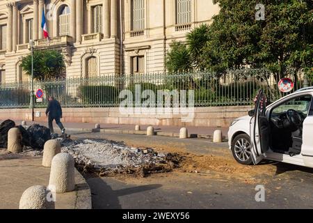 Montpellier, France, 2024. Un homme essaie de repousser les feux allumés par des agriculteurs en colère qui protestent contre la pression des prix devant la préfecture Banque D'Images