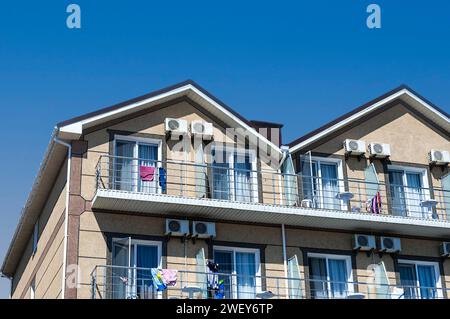 La partie supérieure de la façade d'une maison de deux étages de couleur beige contre un ciel bleu. Banque D'Images