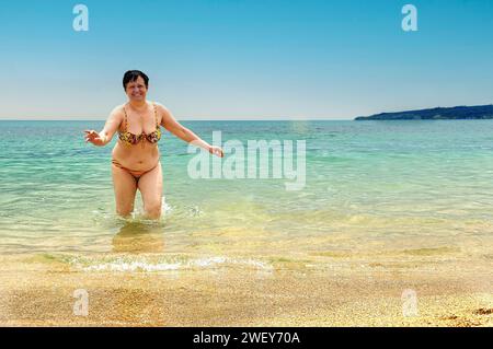 Femme de l'âge de la retraite va de la mer à la plage un jour d'été Banque D'Images