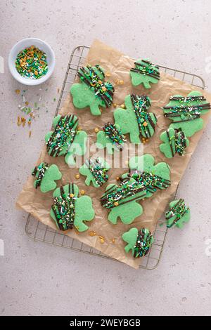 Biscuits Shamrock pour la Saint Patricks avec glaçage au chocolat et saupoudrages, biscuits aux feuilles de trèfle vert sur papier parchemin Banque D'Images