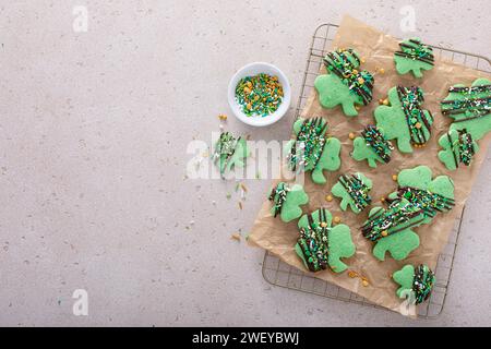 Biscuits Shamrock pour la Saint Patricks avec glaçage au chocolat et saupoudrages, biscuits aux feuilles de trèfle vert sur papier parchemin Banque D'Images