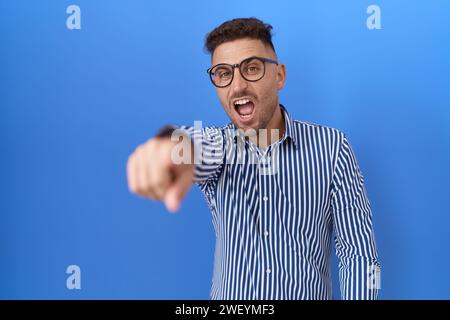 Homme hispanique avec barbe portant des lunettes pointant mécontent et frustré à la caméra, en colère et furieux contre vous Banque D'Images