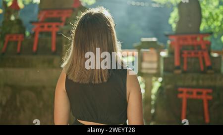 Belle femme hispanique brune dans des verres, s'éloignant lors d'une promenade décontractée à fushimi inari-taisha, le sanctuaire sacré de kyoto du japon, une vie passionnante Banque D'Images