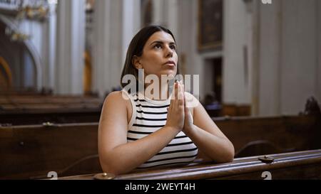 Jeune belle femme hispanique priant sur un banc d'église à l'église des Augustins à Vienne Banque D'Images