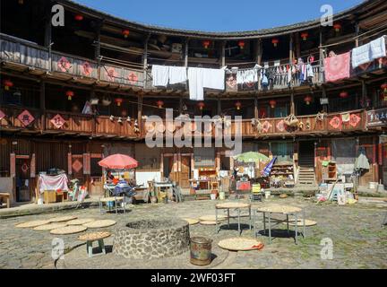 Séchage de la récolte et du grain dans la cour d'un Hakka Tulou (bâtiment en terre battue et bois) dans le comté de Nanjing, Fujian, Chine Banque D'Images