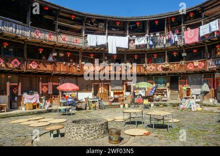 Séchage de la récolte et du grain dans la cour d'un Hakka Tulou (bâtiment en terre battue et bois) dans le comté de Nanjing, Fujian, Chine Banque D'Images