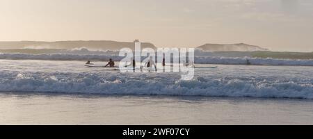 Groupe de surfeurs novices apprenants au coucher du soleil à Essaouira, Maroc, le 27 janvier 2024 Banque D'Images
