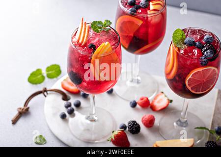 Sangria aux baies dans des verres à vin avec des oranges, des fraises et une variété de baies Banque D'Images