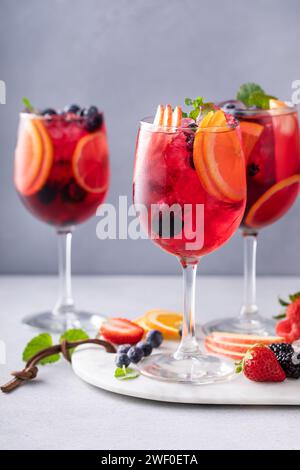 Sangria aux baies dans des verres à vin avec des oranges, des fraises et une variété de baies Banque D'Images