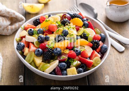Salade de fruits saine et colorée avec banane, ananas, baies, vinaigrette à l'orange et menthe fraîche Banque D'Images