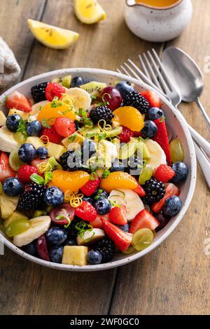 Salade de fruits saine et colorée avec banane, ananas, baies, vinaigrette à l'orange et menthe fraîche Banque D'Images