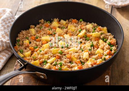 Riz frit à l'ananas avec œufs, carottes et petits pois dans une poêle Banque D'Images