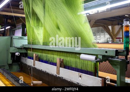 Usine moderne de tissage de tapis. Aiguille pour machine de fabrication de tapis. Bobines de fil attachées à un métier à tisser de tapis. Intérieur intérieur d'un tissu tissé Fa Banque D'Images