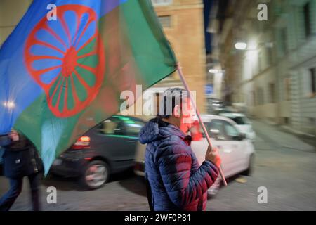 Rome, Italie. 27 janvier 2024. Un homme porte le drapeau international du peuple ROM lors de la procession à la mémoire des victimes oubliées de l'Holocauste à Rome. Procession aux flambeaux à Rome en mémoire, outre le massacre du peuple juif, de toutes les victimes des massacres oubliés : Roms, Sinti, homosexuels, transsexuels, handicapés, les religieux et les opposants politiques déportés et exterminés dans les camps de concentration nazis pendant la Seconde Guerre mondiale. Crédit : ZUMA Press, Inc./Alamy Live News Banque D'Images