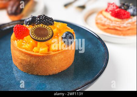 Délicieuses tartelettes avec des baies sur une assiette sur une table blanche, gros plan Banque D'Images