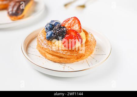 Délicieuse pâte feuilletée avec de la crème et des baies sur une assiette blanche. Banque D'Images