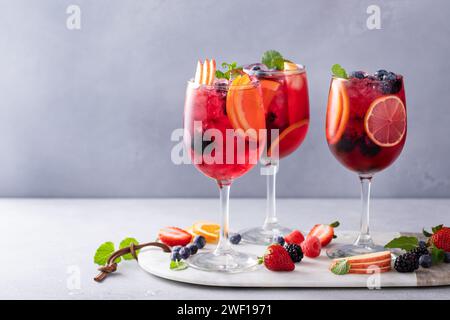 Sangria aux baies dans des verres à vin avec des oranges, des fraises et une variété de baies Banque D'Images