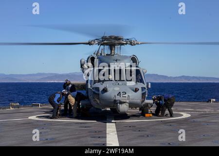 Les marins utilisent des cales et des chaînes pour sécuriser un SH-60S Seahawk, attaché à l'hélicoptère Sea combat Squadron (HSC) 23, au pont d'envol du navire amphibie de débarquement à quai USS Harpers Ferry (LSD 49), alors qu'il se dirigeait dans l'océan Pacifique, le 11 janvier 2024. Le Boxer Amphibious Ready Group, composé de l'USS Boxer (LHD 4), de l'USS Somerset (LPD 25) et de Harpers Ferry, et de la 15e Marine Expeditionary Unit embarquée, mènent des opérations de routine et d'entraînement intégrées dans la 3e flotte américaine. (Photo de l'US Navy par le spécialiste des communications de masse de 2e classe sang Kim) Banque D'Images