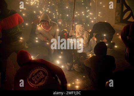 Barcelone, Espagne. 27 janvier 2024, Barcelone, Espagne : les fêtards réagissent alors que les démons font exploser des pyrotechniques lors d'un correfoc pour la célébration du Festival Els Foguerons dans le quartier Gracia de Barcelone. Le Festival des Els Foguerons de sa Pobla est une célébration majorquine qui se tient dans le quartier de Gracia à Barcelone depuis 1993 et met en vedette le folklore catalan avec des personnages traditionnels comme les diables et les correfocs (une vieille tradition catalane où les gens habillés en diables font exploser des pétards et des fusées éclairantes). Crédit : Jordi Boixareu/Alamy Life News Banque D'Images