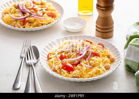 Courge spaghetti aux pois chiches et tomates garnie d'oignon rouge, faible teneur en glucides et idée de recette végétalienne Banque D'Images