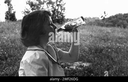 Une jeune fille boit une bouteille en verre de Coca Cola, 1950 ans. Banque D'Images