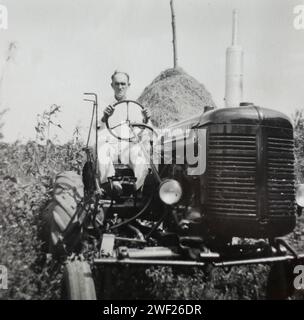 Un homme est assis au sommet de son tracteur Farmall, CA. 1950. Banque D'Images