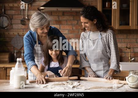 Trois générations féminines petite fille sa maman grand-mère roulent la pâte Banque D'Images