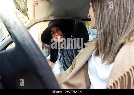 Vue latérale de deux amis assis à l'intérieur d'une voiture heureux de se voir Banque D'Images