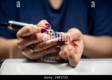 Gros plan d'une femme caucasienne méconnaissable qui remplit ses propres ongles, des clous de bricolage Banque D'Images