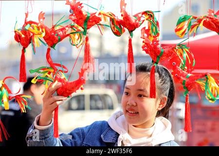 Zaozhuang, Chine. 28 janvier 2024. Une fille sélectionne un ''poulet printanier'' cousu à la main par un artiste folklorique lors d'une foire commerciale du nouvel an à Zaozhuang, dans la province du Shandong, en Chine, le 28 janvier 2024. (Photo Costfoto/NurPhoto) crédit : NurPhoto SRL/Alamy Live News Banque D'Images