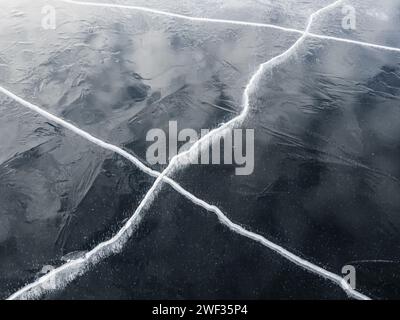 Une vue rapprochée révèle le réseau complexe de fissures et de fissures sur la surface glacée d'un lac gelé. Banque D'Images