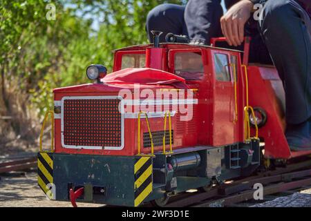 Jeune adulte avec l'uniforme de maître de la gare à bord d'un train jouet de calibre 5 pouces Banque D'Images