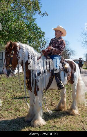 Cow-boy assis en selle au sommet d'un cheval avec la crinière tressée, attendant le début de la 92e édition annuelle Texas Citrus Fiesta Parade of oranges, Mission, Texas, USA. Banque D'Images
