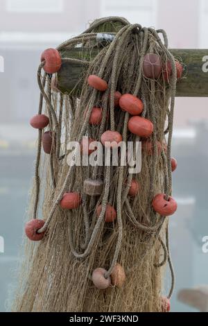 Une série de filets de pêche accrochés près du port près des bateaux de pêche après un voyage de pêche. Filets reliés par des cordes en plastique et des flotteurs de différentes couleurs Banque D'Images