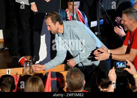 Kirchweidach, Allemagne. 28 janvier 2024. Football : Bundesliga, FC Bayern Munich. Le joueur du FC Bayern Harry Kane, originaire d'Angleterre, pousse une tasse à bière au fan club 'Die Roten' à Kirchweidach. Il a reçu un trophée pour sa victoire dans un mini-olympique bavarois sous la forme d'une couronne de buteur de buts, qu'il pouvait également utiliser pour profiter du tabac à priser. Les stars du FC Bayern ont compensé leurs visites au fan club, qui avaient été reportées en décembre en raison de la météo hivernale. Crédit : -/Jens Niering/dpa/Alamy Live News Banque D'Images