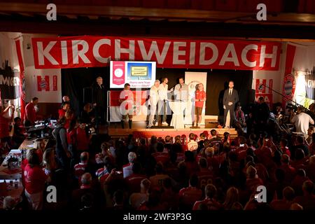 Kirchweidach, Allemagne. 28 janvier 2024. Football : Bundesliga, FC Bayern Munich. Le joueur du FC Bayern Harry Kane d'Angleterre se tient sur une scène avec des fans au fan club 'Die Roten' à Kirchweidach. Il a reçu un trophée pour sa victoire dans un mini-olympique bavarois sous la forme d'une couronne de buteur de buts, qu'il pouvait également utiliser pour profiter du tabac à priser. Les stars du FC Bayern ont compensé leurs visites au fan club, qui avaient été reportées en décembre en raison de la météo hivernale. Crédit : -/Jens Niering/dpa/Alamy Live News Banque D'Images