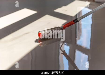 Rouleau à aiguilles pour sols auto-nivelants. Nivellement des sols avec un mélange de ciment. Banque D'Images