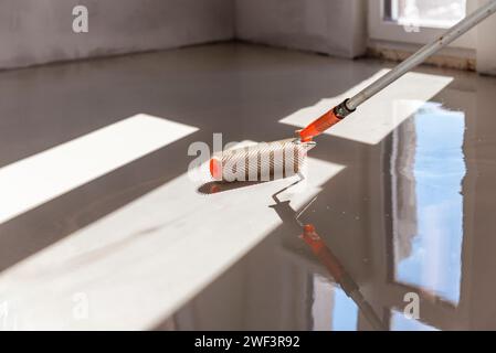 Rouleau à aiguilles pour sols auto-nivelants. Nivellement des sols avec un mélange de ciment. Banque D'Images