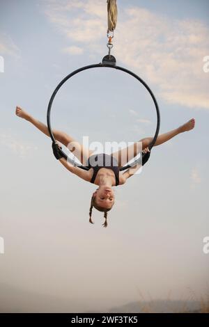 gymnaste fille de 12 ans exécutant sur le cerceau aérien à l'extérieur Banque D'Images