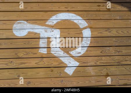 Le symbole international de l'accès (ISA) ou le symbole international des fauteuils roulants en blanc peint sur une terrasse en bois Banque D'Images