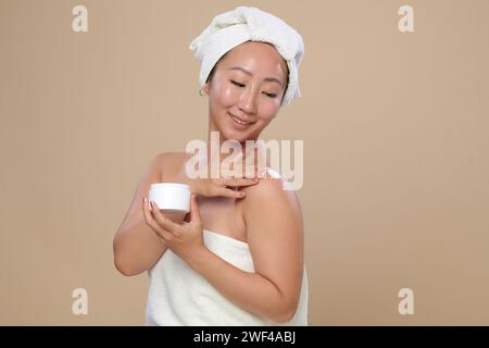 Portrait de jeune femme souriante appliquant une lotion pour le corps après la douche Banque D'Images
