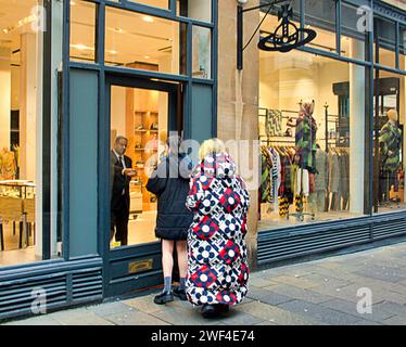 Glasgow, Écosse, Royaume-Uni. 23 janvier 2024. UK Météo : jour misérable reflété dans les rues dystopiques alors que les habitants luttent dans un environnement en décomposition. Le magasin Vivienne westwood sur le mile de style obtient des clients élégants. Crédit Gerard Ferry/Alamy Live News Banque D'Images