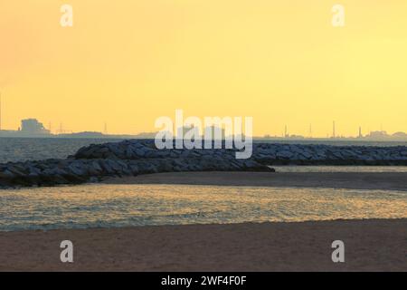 Brise-lames côtier dans la soirée qui a une lueur orange du coucher du soleil couchant. Banque D'Images